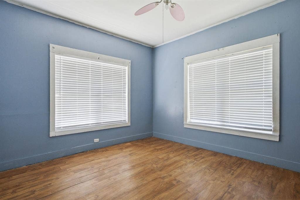 506 E Longview Street, Arp, TX 75750 Wood-finish flooring with blue wall tones, two large windows, and a ceiling fan fixture