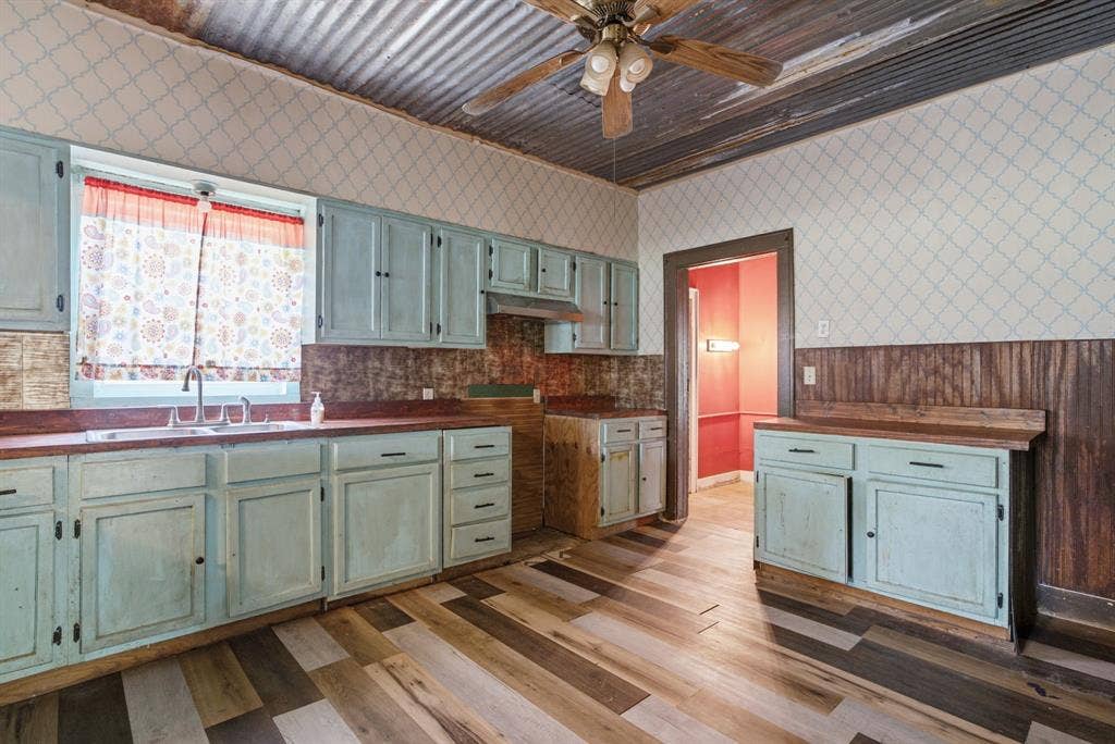 506 E Longview Street, Arp, TX 75750 Kitchen with corrugated metal ceiling, patterned wallpaper, wood-finish flooring, and light blue cabinetry