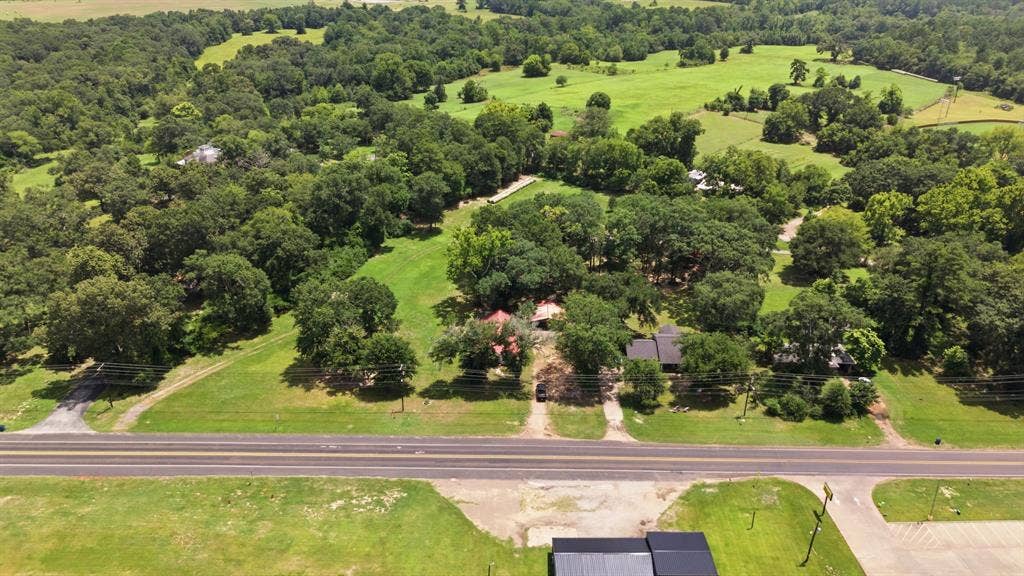506 E Longview Street, Arp, TX 75750 Expansive green landscape with significant tree coverage and multiple structures