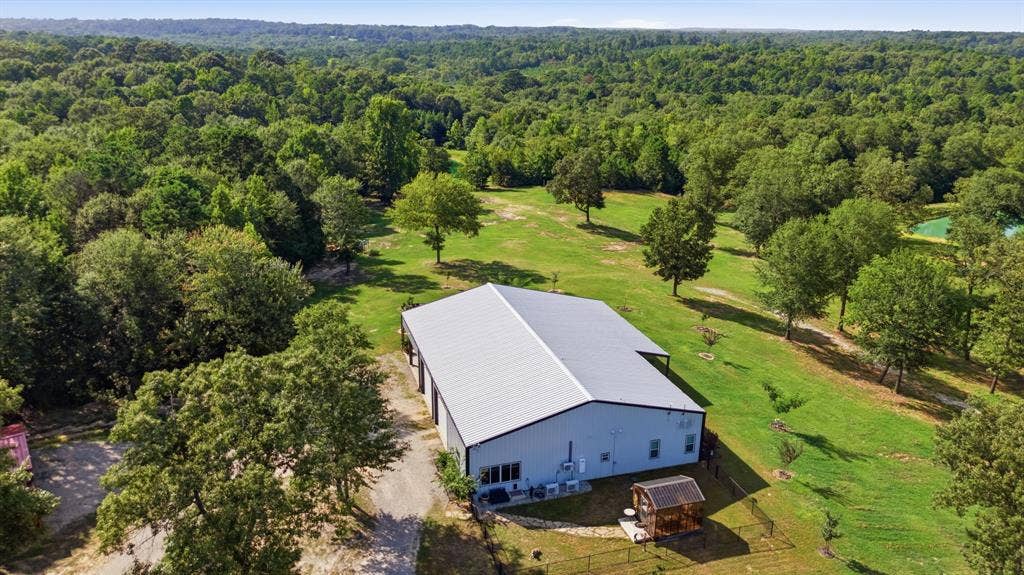 12842 Farm to Market 838, Overton, TX 75684 Expansive green space with mature trees, a metal-roof structure, and surrounding wooded areas
