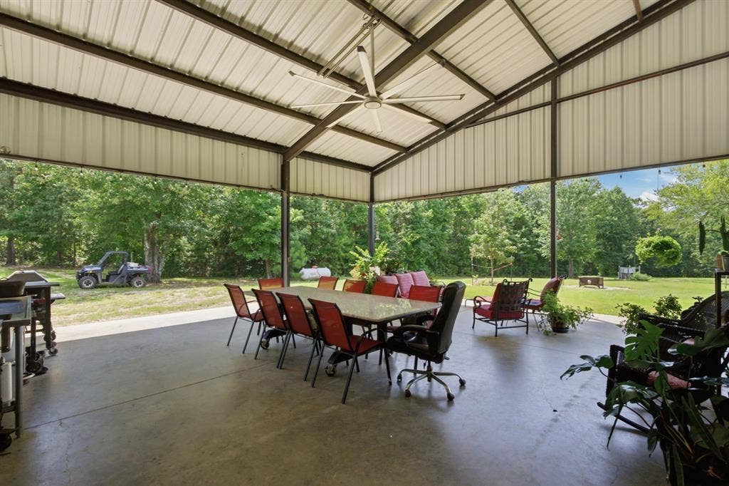 12842 Farm to Market 838, Overton, TX 75684 Expansive covered patio featuring a metal roof structure, concrete flooring, and a large ceiling fan