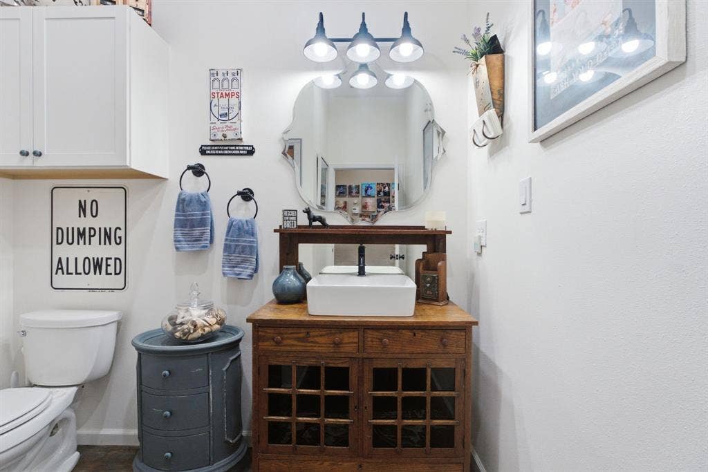 12842 Farm to Market 838, Overton, TX 75684 White shaker-style cabinetry, a vanity with a vessel sink, a decorative mirror, and a wall-mounted light fixture