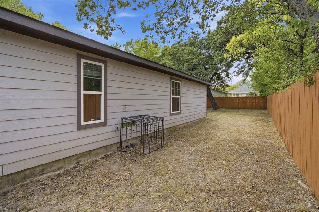 3923 Metropolitan Avenue, Dallas, TX 75210 Exterior wall with light gray siding, white-framed windows with dark trim, and a brown roofline