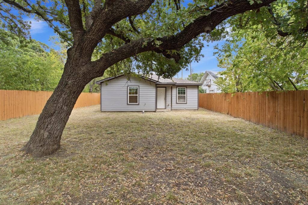 3923 Metropolitan Avenue, Dallas, TX 75210 Expansive backyard featuring a mature tree, wood fencing, and a compact exterior