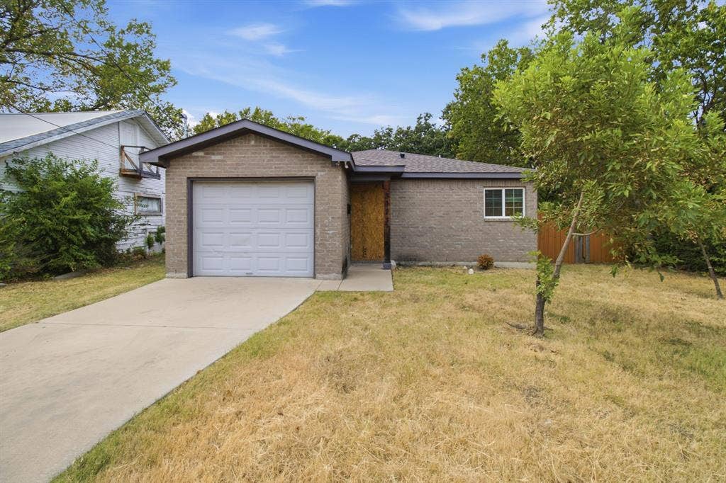 3923 Metropolitan Avenue, Dallas, TX 75210 Brick exterior, attached garage, single-pane window, concrete driveway, and a partially fenced yard