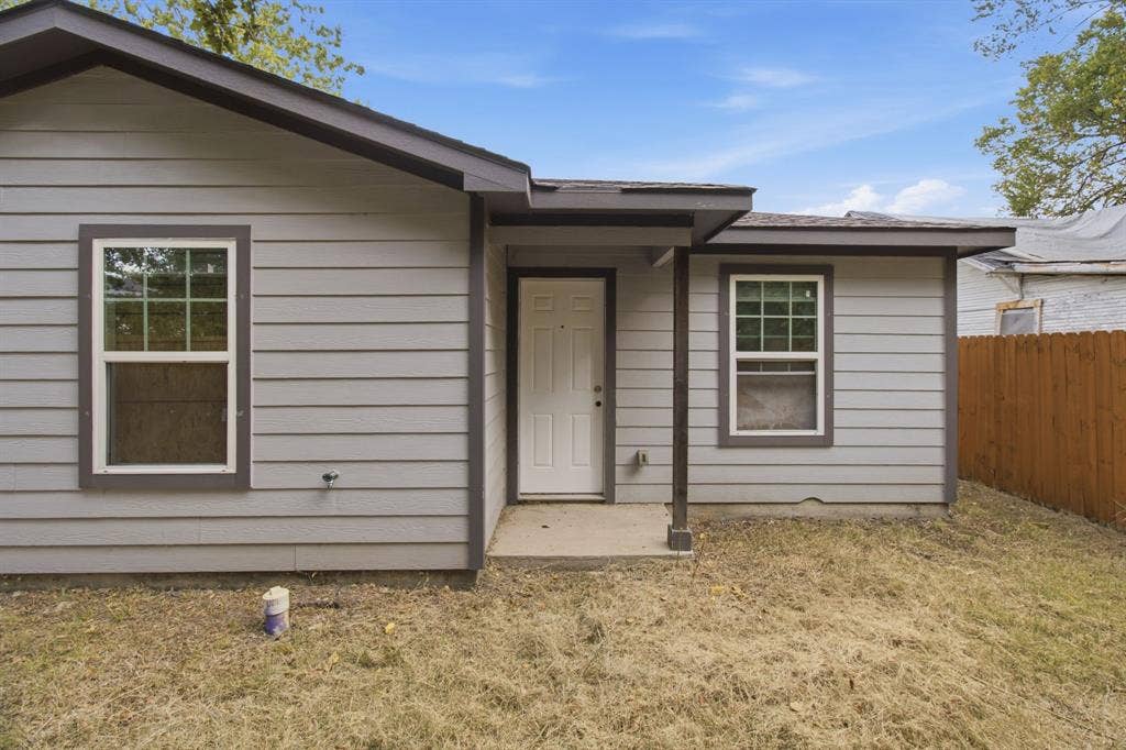 3923 Metropolitan Avenue, Dallas, TX 75210 Gray siding exterior with contrasting trim, multiple windows with grids, and a covered entry