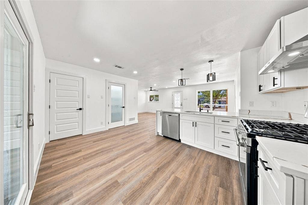 Kitchen featuring white cabinetry, stainless steel appliances, wood-finish flooring, recessed lighting, and a gas range
