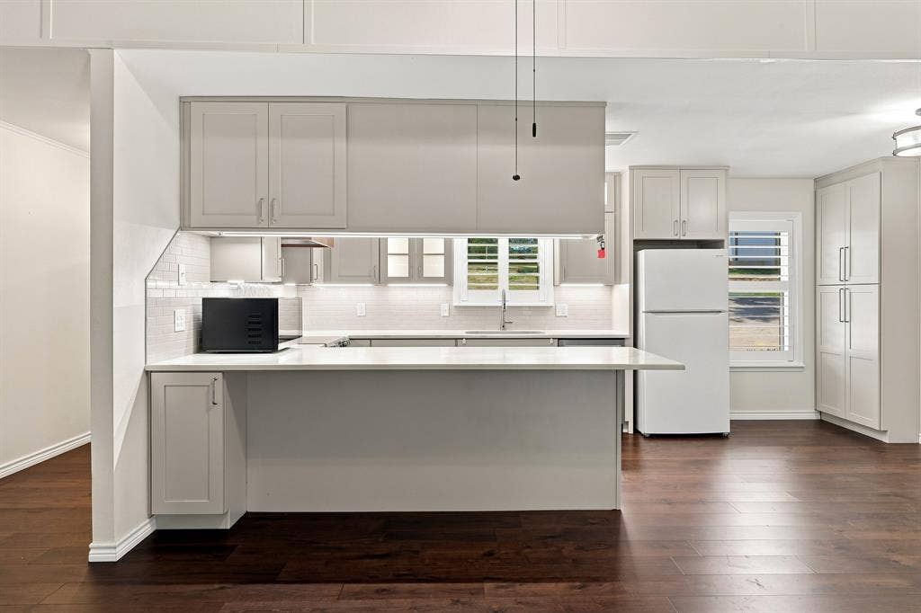 21121 County Road 1291, Flint, TX 75762 Contemporary kitchen featuring light gray shaker-style cabinetry, a white subway tile backsplash, a peninsula with a white countertop, and dark wood-finish flooring