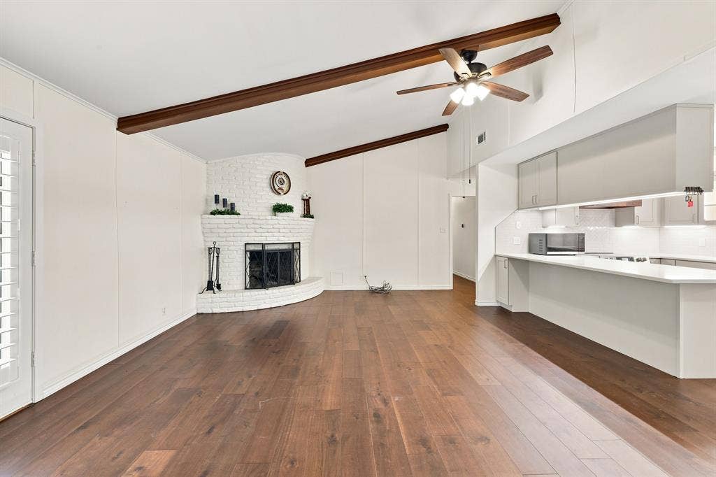 21121 County Road 1291, Flint, TX 75762 Vaulted ceiling with exposed wood beams, wood-finish flooring, white brick fireplace, modern kitchen cabinetry, and recessed lighting