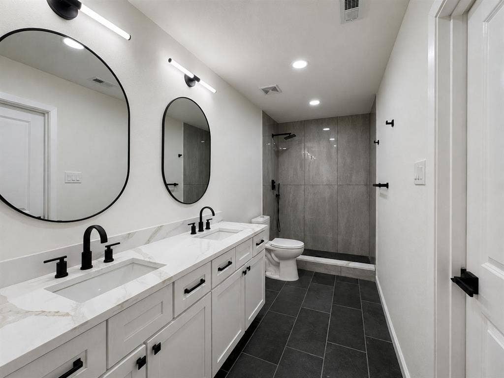 1842 Delmar Drive, Garland, TX 75040 Dual vanity with white shaker cabinetry, integrated rectangular sinks, and matte black fixtures