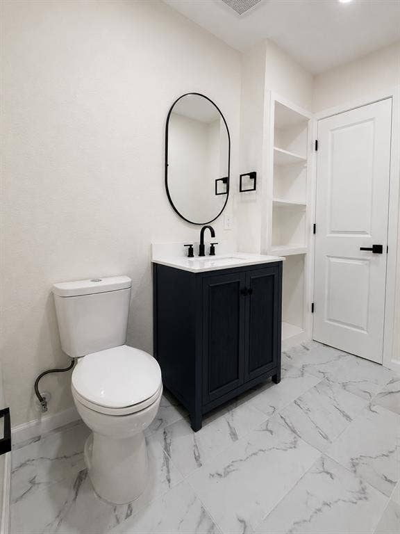 1842 Delmar Drive, Garland, TX 75040 White-veined flooring, vanity with dark cabinetry, modern oval mirror, built-in shelving, and contemporary black fixtures