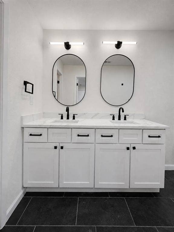 1842 Delmar Drive, Garland, TX 75040 Dual vanity with white shaker-style cabinetry, matte black hardware, and a light-toned countertop