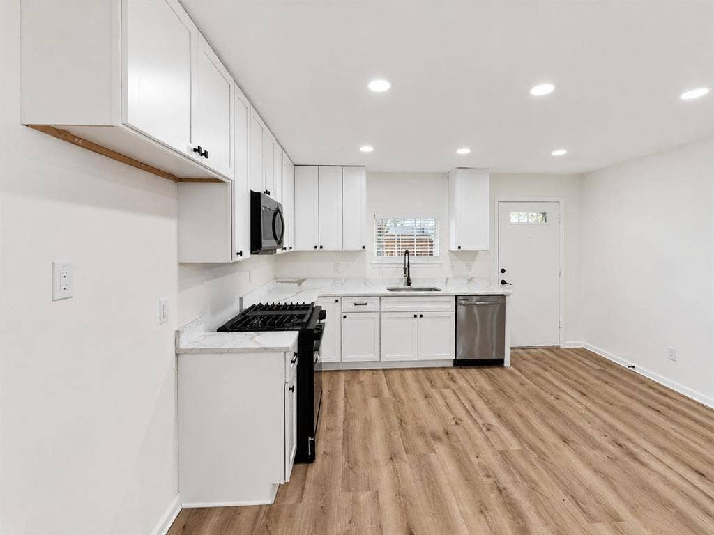 1842 Delmar Drive, Garland, TX 75040 Modern kitchen featuring white cabinetry, light-toned countertops, stainless steel appliances, and wood-finish flooring
