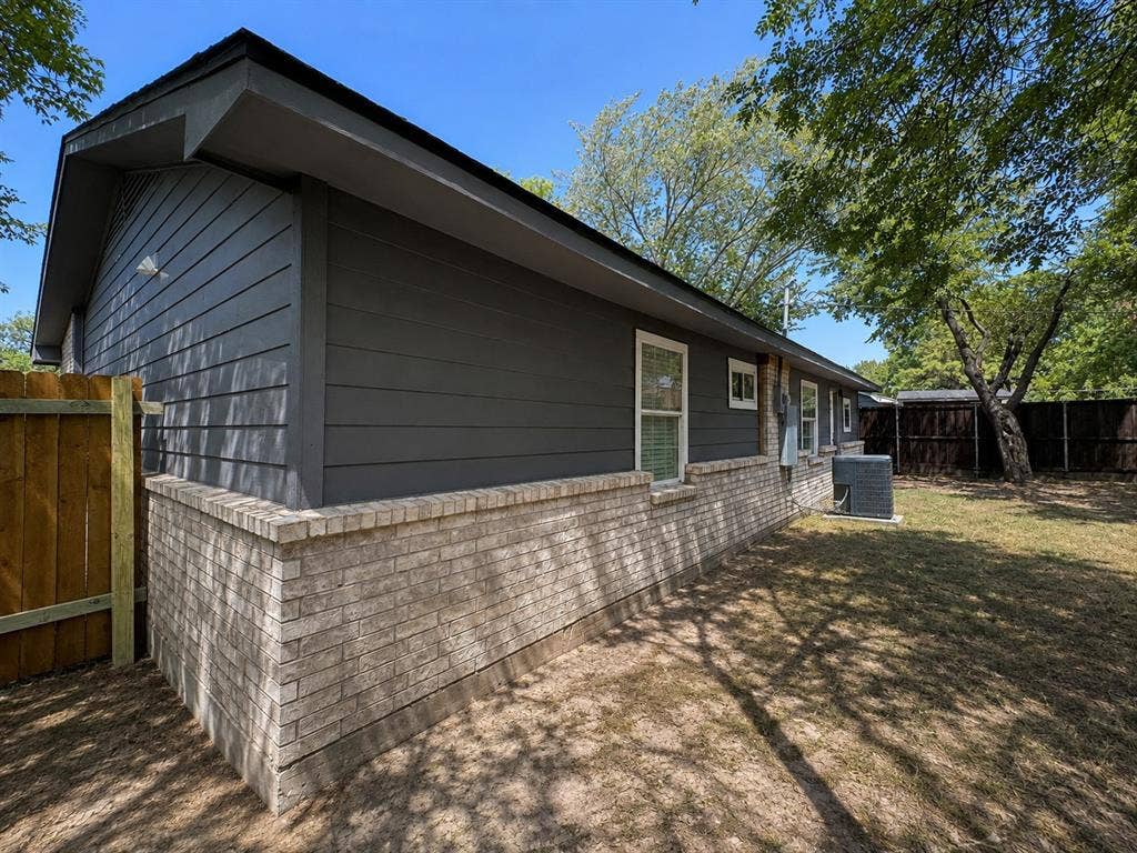 1842 Delmar Drive, Garland, TX 75040 Exterior featuring horizontal siding, brick wainscoting, and a wood privacy fence