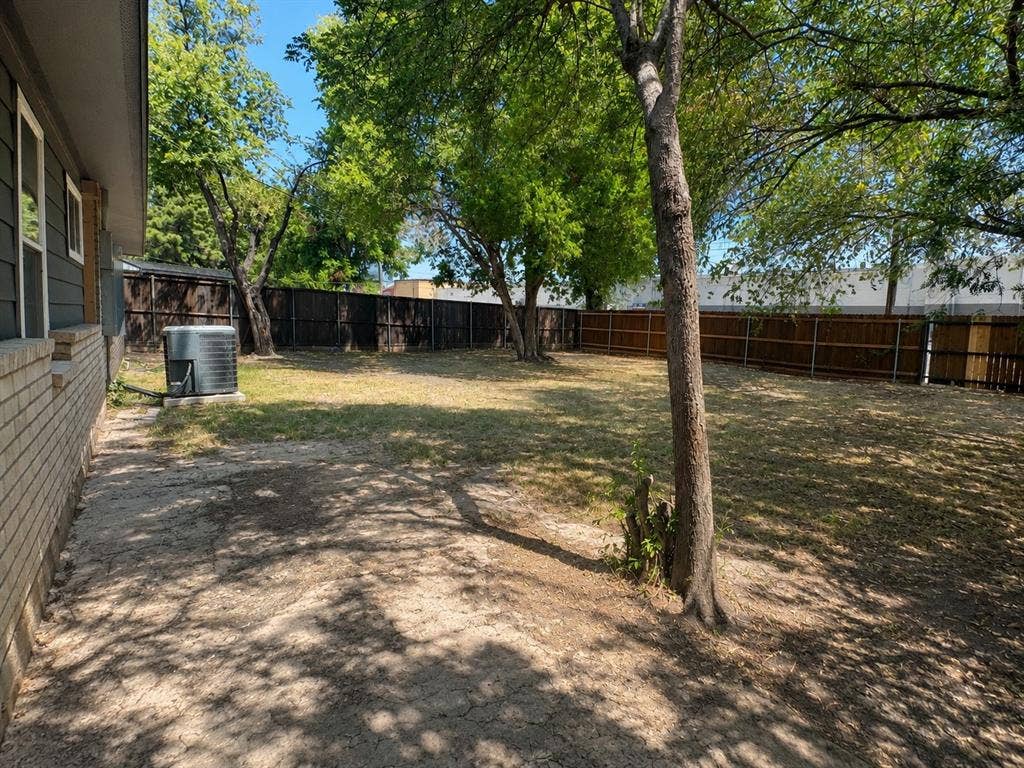 1842 Delmar Drive, Garland, TX 75040 Expansive backyard with a full privacy fence, mature trees, and a brick and siding exterior