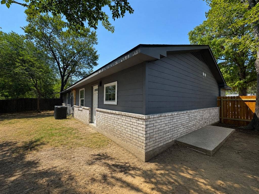 1842 Delmar Drive, Garland, TX 75040 Modern ranch-style home featuring a charcoal fiber cement exterior with contrasting brick veneer foundation