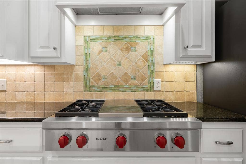 367 Elm Grove Circle, Waco, TX 76657 Stainless steel range, stone tile backsplash with decorative inset, granite countertops, white cabinetry with silver hardware, and under-cabinet lighting