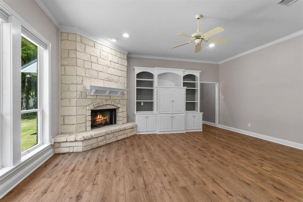 367 Elm Grove Circle, Waco, TX 76657 Corner stone fireplace with hearth, built-in cabinetry, wood-finish flooring, and ceiling fan