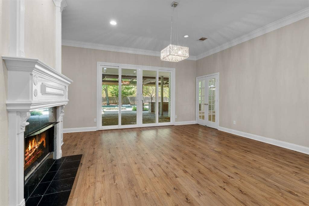 367 Elm Grove Circle, Waco, TX 76657 Wood-finish flooring, white fireplace with a black tile hearth, crown molding, double French doors, and sliding glass doors