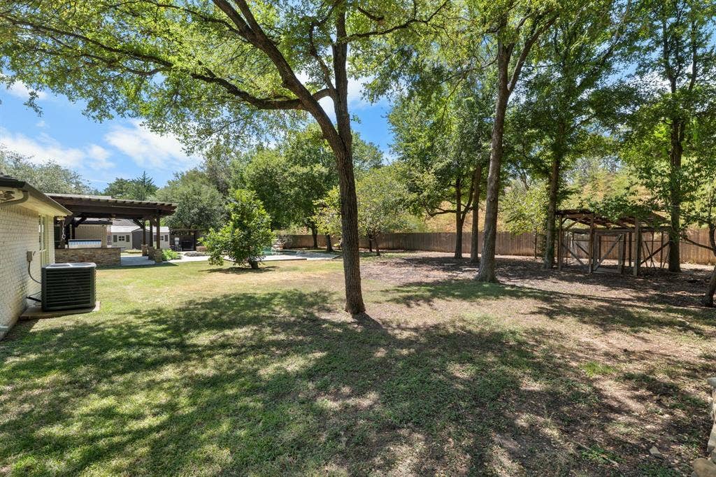367 Elm Grove Circle, Waco, TX 76657 Expansive backyard featuring mature trees, a wooden pergola, and a privacy fence