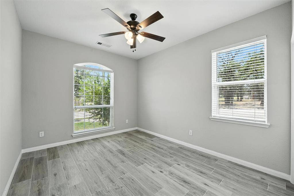 Secondary bedroom with light gray walls and wood-finish tile flooring