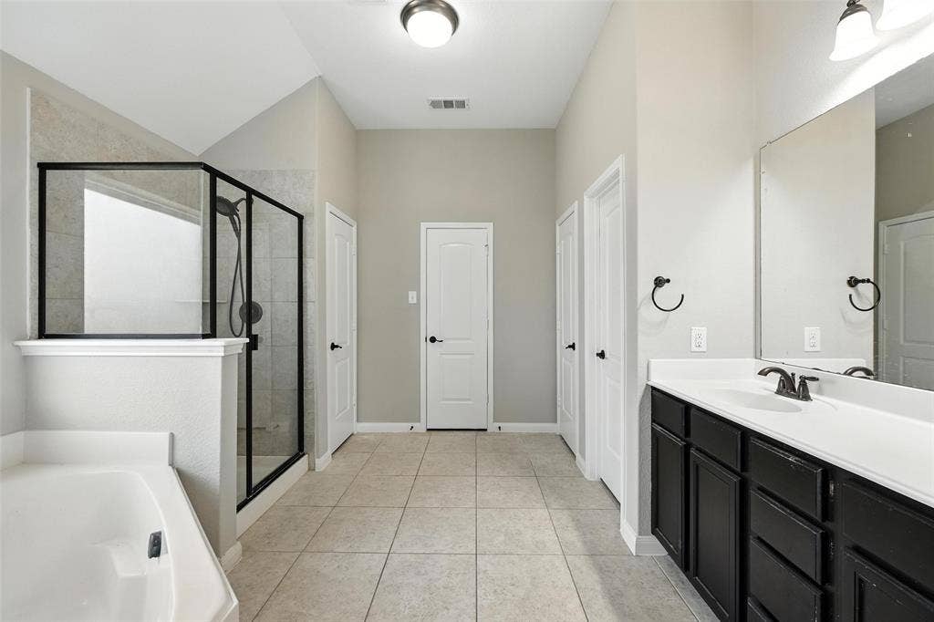 Recessed tub with an adjacent glass-enclosed shower featuring a black frame