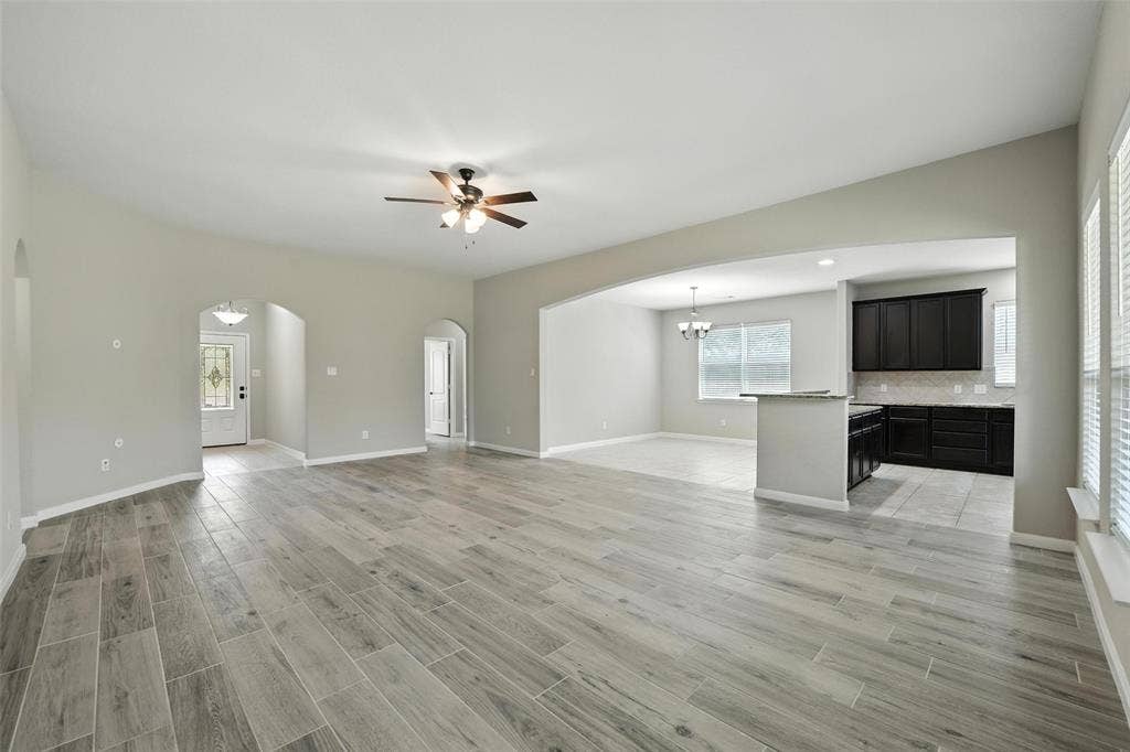 Open-concept living area featuring wood-finish flooring, recessed lighting, and an arched entryway