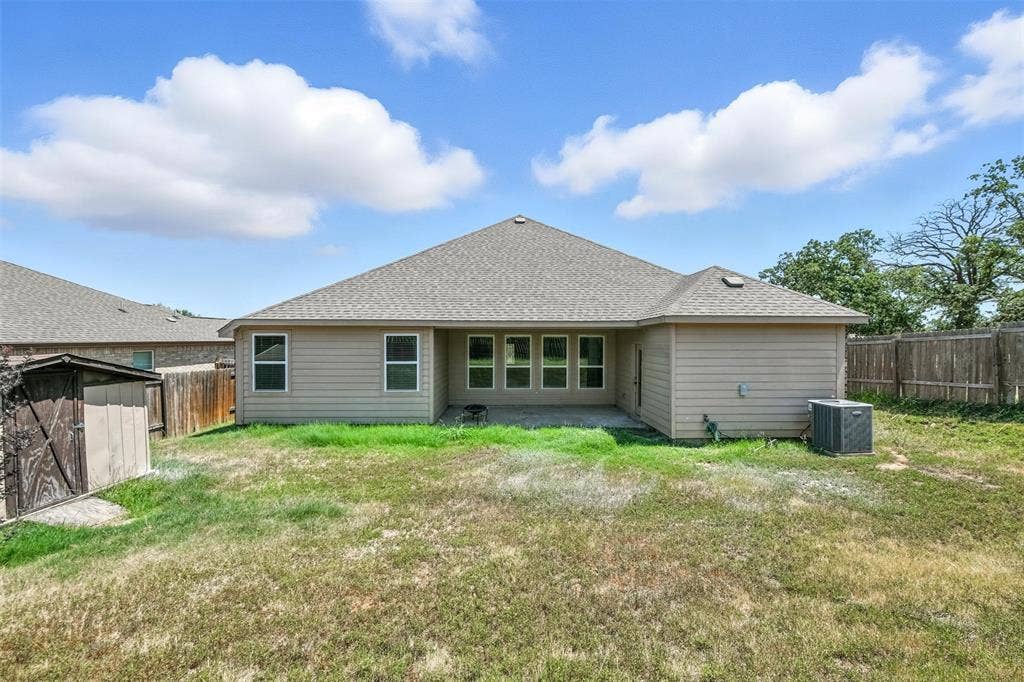 Rear exterior featuring a covered patio, multiple windows, and a fenced perimeter