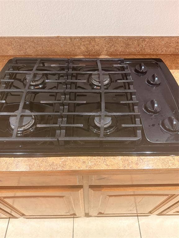 1111 Whitaker Way, Glenn Heights, TX 75154 Black four-burner gas cooktop with cast iron grates, solid surface countertop, and wood-finish cabinetry