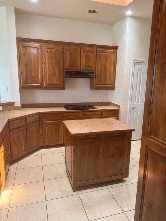 1111 Whitaker Way, Glenn Heights, TX 75154 Kitchen featuring wood-finish cabinetry, a built-in cooktop, a central island, and tiled flooring