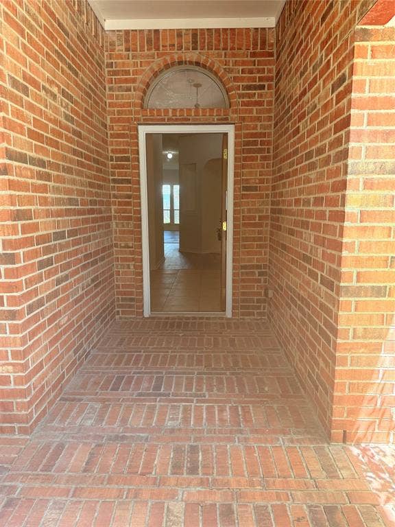 1111 Whitaker Way, Glenn Heights, TX 75154 Brick exterior featuring a recessed entry, arched transom window, and brick-patterned flooring