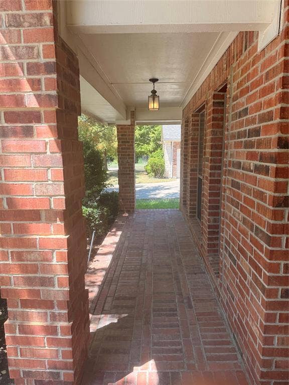 1111 Whitaker Way, Glenn Heights, TX 75154 Brick exterior with a covered porch featuring a brick-patterned walkway and a suspended light fixture