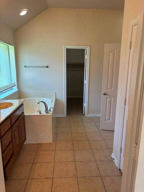 1111 Whitaker Way, Glenn Heights, TX 75154 Built-in soaking tub with chrome fixtures, wood-finish vanity with countertop, tile flooring, and vaulted ceiling with recessed lighting