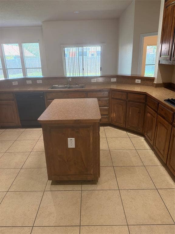 1111 Whitaker Way, Glenn Heights, TX 75154 Kitchen featuring wood cabinetry, an integrated sink with a window above, a central island, tile flooring, and a built-in dishwasher