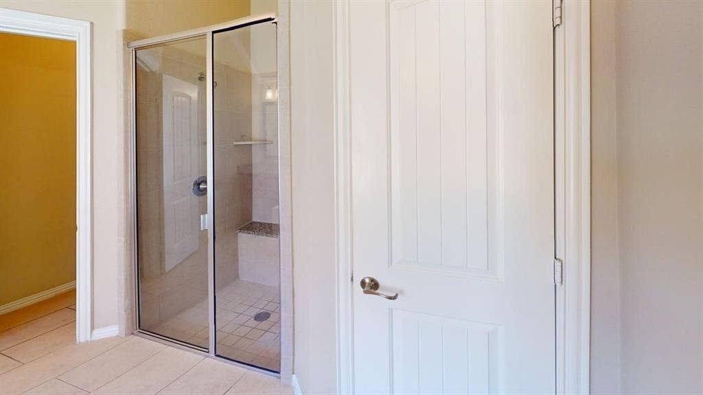 Shower enclosure with sliding glass doors, tiled walls, built-in bench, and tiled flooring