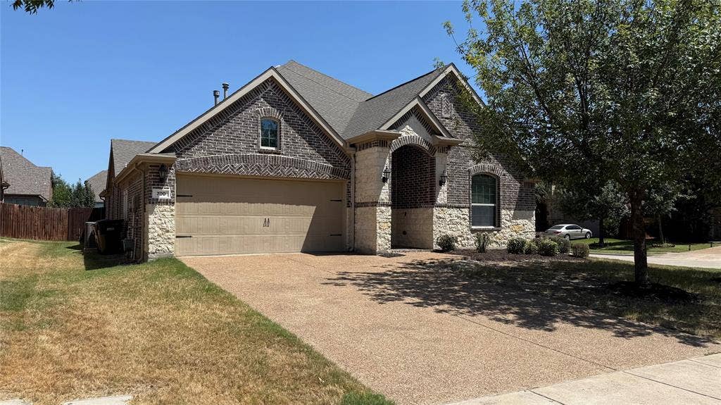 Traditional architecture featuring a brick and stone facade, arched entryway, and an attached two-car garage