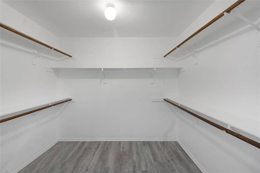 408 Centennial Place, Crowley, TX 76036 Walk-in closet featuring wood-finish flooring, white walls, and built-in shelving with hanging rods