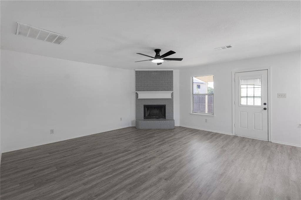 408 Centennial Place, Crowley, TX 76036 Wood-finish flooring, brick-faced fireplace with mantle, ceiling fan with integrated lighting, rear exterior door with glass inserts, and a window providing natural illumination