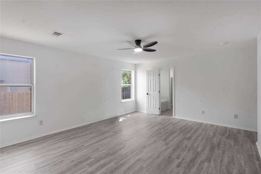408 Centennial Place, Crowley, TX 76036 Spacious interior with neutral white walls, wood-finish flooring, multiple windows, and a ceiling fan