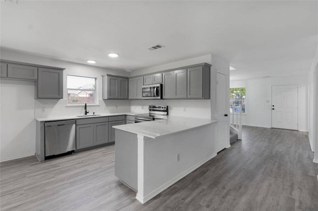 408 Centennial Place, Crowley, TX 76036 Kitchen featuring gray cabinetry, white countertops, stainless steel appliances, and wood-finish flooring