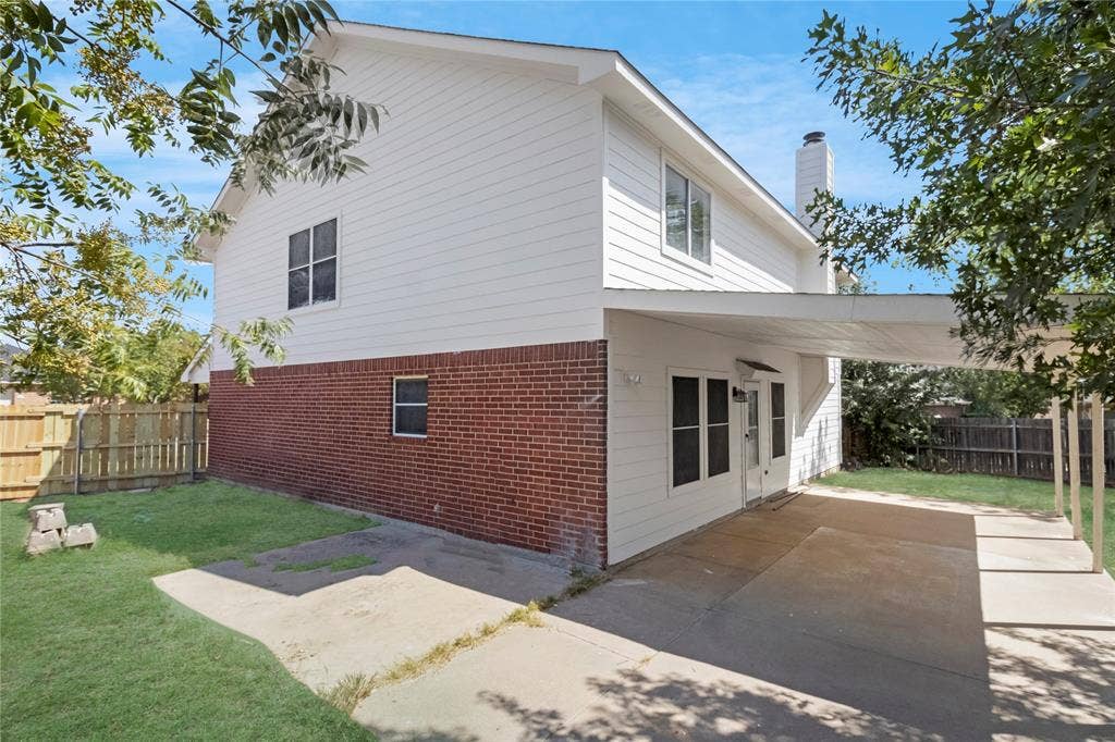 408 Centennial Place, Crowley, TX 76036 Two-story exterior with a brick and white siding facade, featuring a patio area with a covered extension, and a wood privacy fence