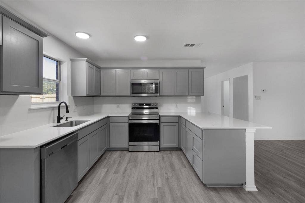 408 Centennial Place, Crowley, TX 76036 U-shaped kitchen featuring grey cabinetry, white countertops, stainless steel appliances, and wood-finish flooring