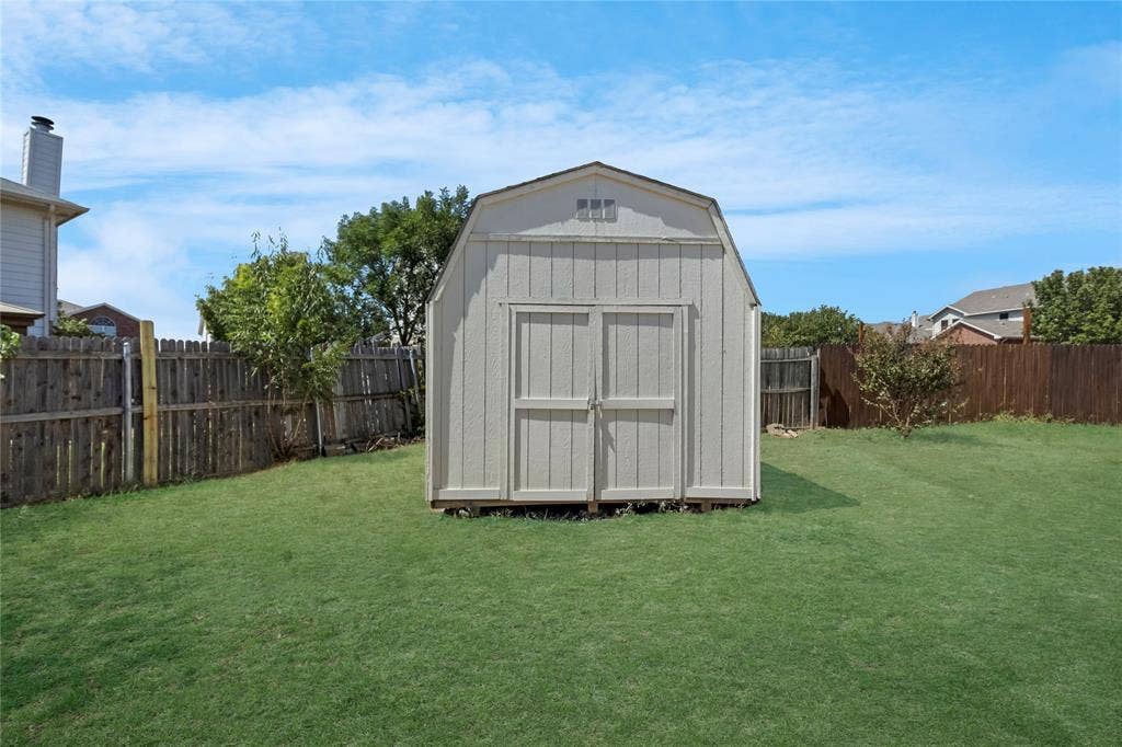 408 Centennial Place, Crowley, TX 76036 Expansive lawn featuring a storage shed with double doors and a gable roof