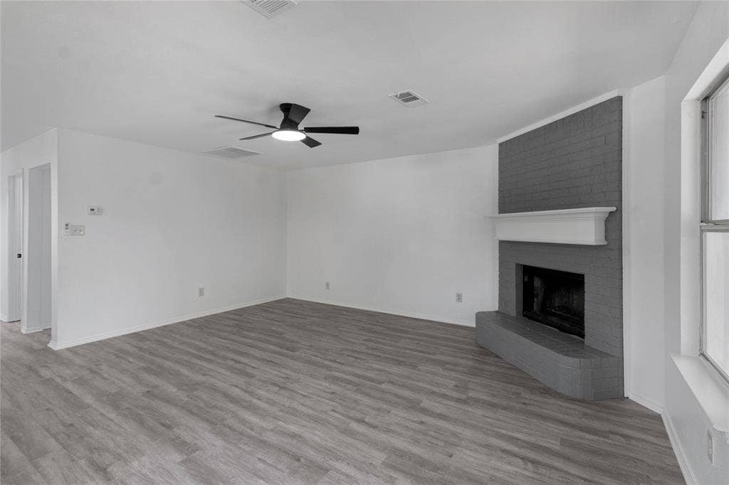 408 Centennial Place, Crowley, TX 76036 Spacious room featuring wood-finish flooring, a contemporary ceiling fan, and a brick fireplace with a white mantel and hearth