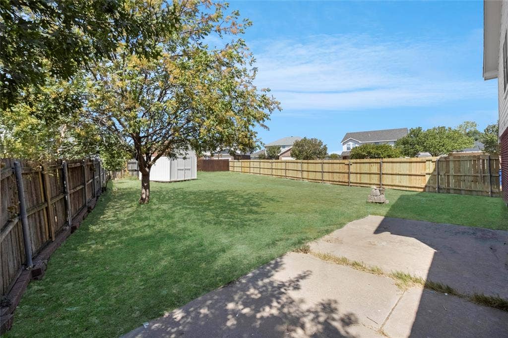 408 Centennial Place, Crowley, TX 76036 Expansive backyard featuring a manicured lawn, established tree, and a concrete patio