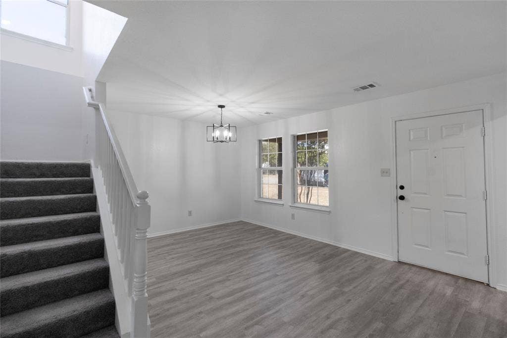408 Centennial Place, Crowley, TX 76036 Wood-finish flooring, staircase with carpeted treads and white handrail, two windows, and a modern chandelier