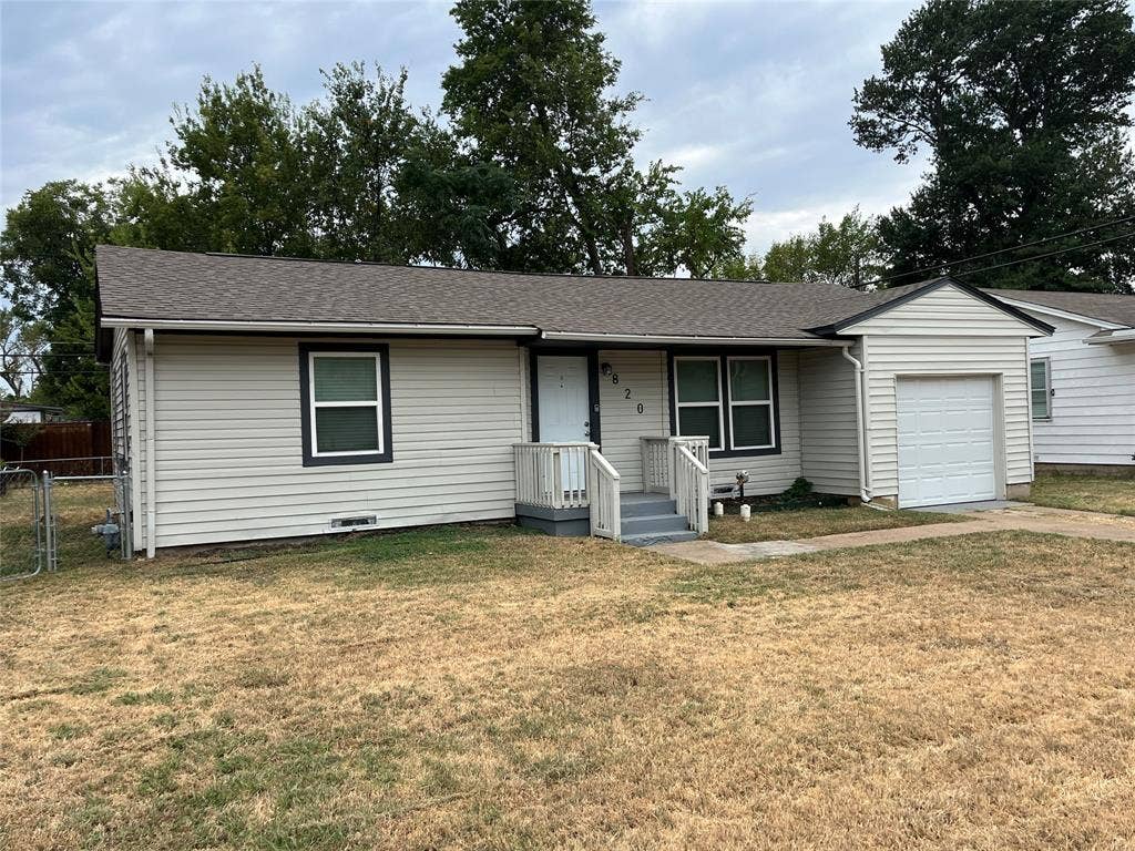 820 E Edith Street, Irving, TX 75061 Light-colored horizontal siding exterior with dark-trimmed windows, a gabled roofline, and an attached garage with a white panel door