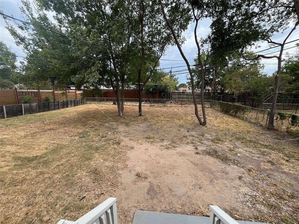820 E Edith Street, Irving, TX 75061 Expansive backyard space with mature trees, perimeter fencing, and a retaining wall