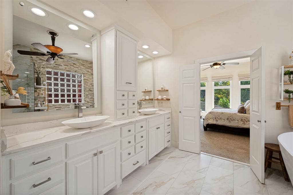 8524 Wellington Point Drive, Irving, TX 75063 Dual vanity with vessel sinks, white cabinetry, stone-finish countertops and white tile flooring.