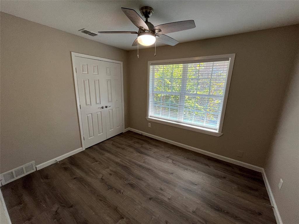 1843 Greendale Drive, Dallas, TX 75217 Room with wood-finish flooring, a window with blinds, and a built-in closet with bi-fold doors